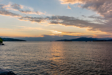 Sunset on the sea in front of Vancouver with container ships, sail boat and stand-up paddles