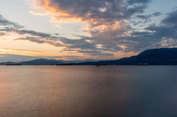 Sunset on the sea in front of Vancouver with container ships, sail boat and stand-up paddles