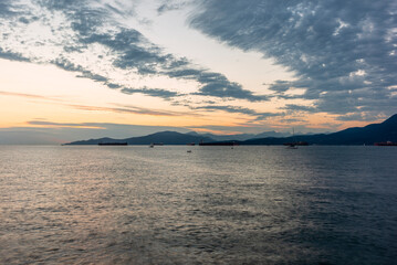 Sunset on the sea in front of Vancouver with container ships, sail boat and stand-up paddles