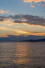 Fototapeta premium Sunset on the sea in front of Vancouver with container ships, sail boat and stand-up paddles