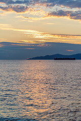 Sunset on the sea in front of Vancouver with container ships, sail boat and stand-up paddles