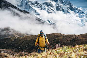 Solo brave traveler walk to mountain summit wearing professional travel equipment. Yong hiker traveling across mountain track among high altitude sunny rock