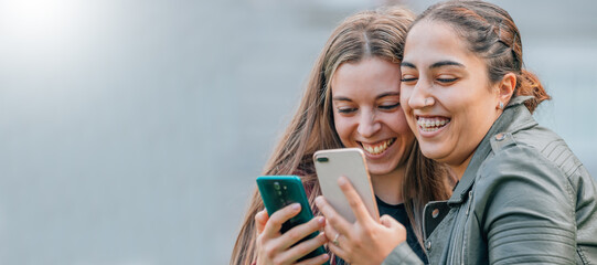 Obraz premium friends with mobile phones smiling hugging in the street