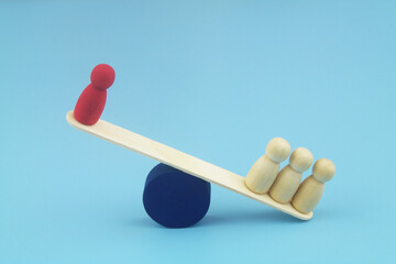 Red and three common wooden people figures balancing on seesaw. on blue background 