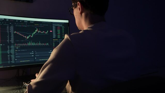 financier works in an online trading terminal, cryptocurrency exchanges and securities exchanges. The investor works late in international markets, a dark cabinet, an image with a small depth of focus