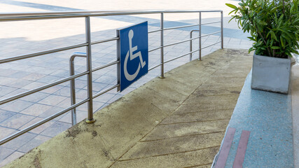 Disabled way sign in front of building. Handicapped sign traffic symbol on the floor in front of ramp way for support wheelchair. Disabled way sign in front of cafe on green nature landscape.