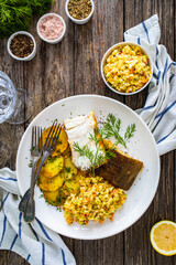 Fish dish - fried halibut with French fries and lemon on wooden table
