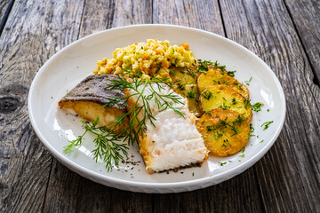 Fish dish - fried halibut with French fries and lemon on wooden table
