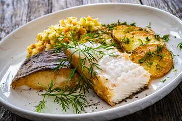 Fish dish - fried halibut with French fries and lemon on wooden table
