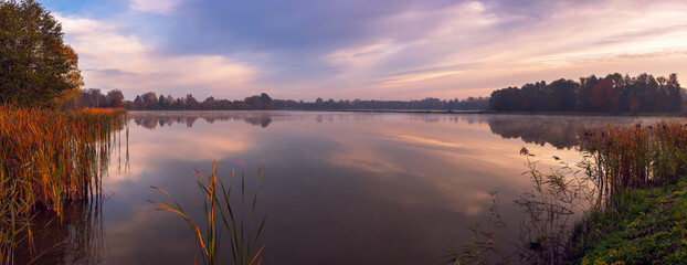 Beautiful ponds at sunrise on a foggy autumn morning. Multicolored sky. Grojec, Poland