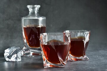 Glasses of cognac and decanter on a gray concrete table. Selective focus. Copy space