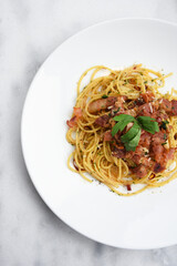 Top view photo Spaghetti with Bacon Chili on white plate at marble table. Spaghetti with Bacon Chili,