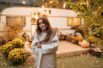 Girl outdoors in warm clothes near the campervan. Beautiful autumn in the forest