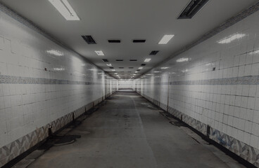 Perspective view of Ambient public underpass with white tiled walls and stripes of ceiling neon...