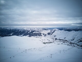 Wide aerial panorama of snowy mountain ridge on winter sunrise. Stunning mountains range covered...