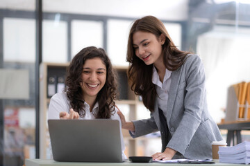 Two young Asian business woman talk, consult, discuss working with new startup project idea presentation analyze plan marketing and investment in the office. - obrazy, fototapety, plakaty