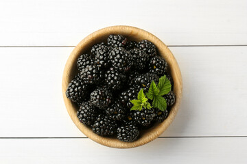 Bowl with fresh ripe blackberries on white wooden table, top view