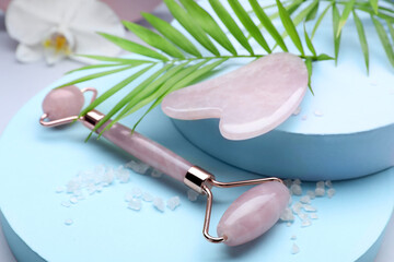 Beautiful composition with gua sha stone and face roller on color background