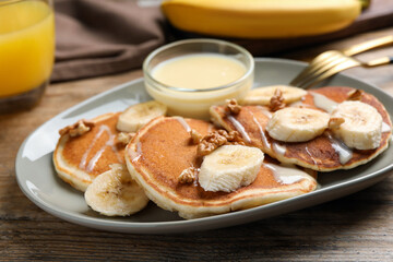 Tasty pancakes with sliced banana served on wooden table, closeup