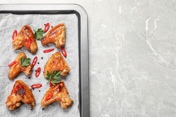 Tray with delicious fried chicken wings on light gray marble table, top view. Space for text