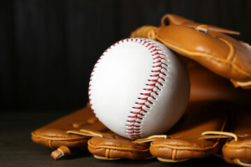 Leather baseball glove with ball on wooden table, closeup