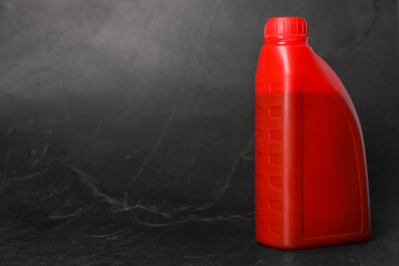 Motor oil in red canister on black background, space for text