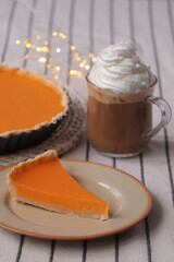 Fresh homemade pumpkin pie and cup of cocoa with whipped cream on table
