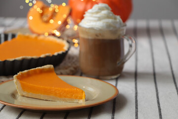 Fresh homemade pumpkin pie and cup of cocoa with whipped cream on table