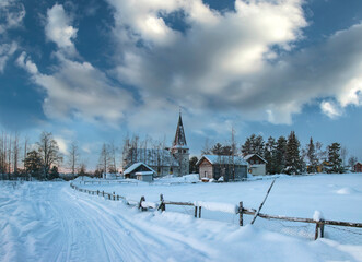 Fototapeta premium Wooden fence and old stone church on a winter day