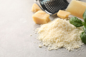 Pile of grated parmesan cheese on light table, closeup. Space for text