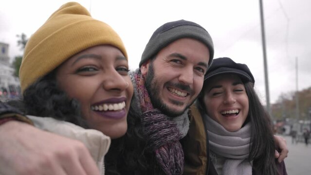 Smiling self-portrait of a three friends in winter clothes taking selfie. Happy human faces. Cheerful people looking at camera. High quality 4k footage