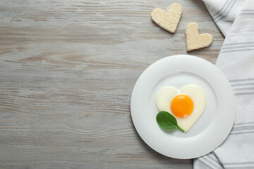 Tasty breakfast with heart shaped fried egg served on white wooden table, flat lay. Space for text