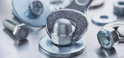 Fotobehang Wrench tightens steel cap nut in steel billet. Spanner, bolt, screw and nuts. © evkaz