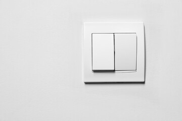 Modern plastic light switch on white wall, space for text