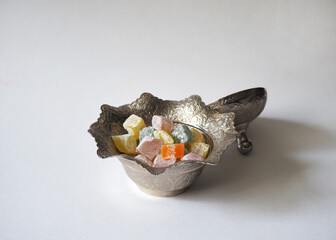 Turkish delights (lokum) in a traditional copper bowl on the blank surface.