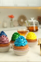 Delicious cupcakes with colorful cream on white board