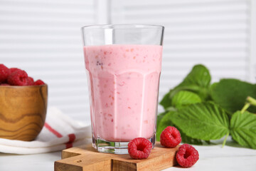 Tasty raspberry smoothie in glass on white table