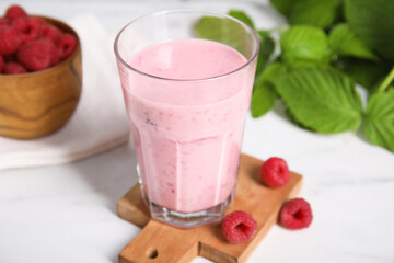 Tasty raspberry smoothie in glass on white table, closeup