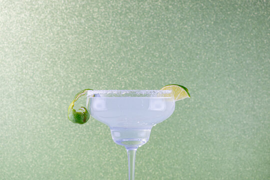 Prepared Glass For Cocktail With Lime And Preparation Instruments On Green Background