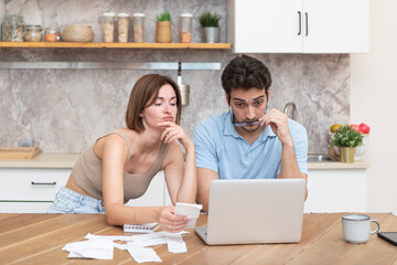 Family financial crisis concept. Shocked and stressed couple counting expenses, taxes and debts....