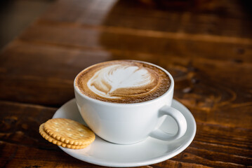 Coffee latte served with a couple of biscuit.