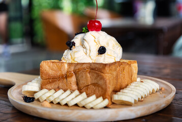 Honey toast, french toast with vanilla ice cream and honey on buttered bread in wooden plate.
