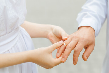 Woman puts a ring on her man finger. The bride gives the wedding ring to the groom. Without face