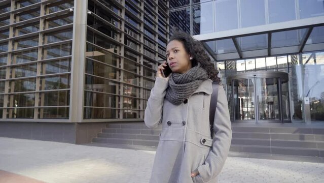 Businesswoman in casual clothing Talking in phone on the Big City Street in the Business District, Checks Her Smartphone. Confident entrepreneur Woman. High quality 4k footage