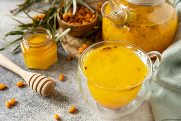 Sea ​​​​buckthorn and cup of healthy sea ​​​​buckthorn tea with honey on a stone...