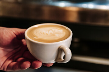 Barista hand hold cup cappuccino Coffee with espresso and milk in cafe