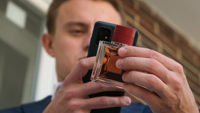 A man scans a qr code on a perfume bottle using a smartphone, close-up