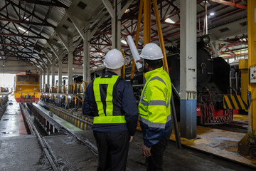 Engineer checking train engine Prepare for repainting for use in train stations. Engineers wear protective clothing and helmets to work safely as standard.
