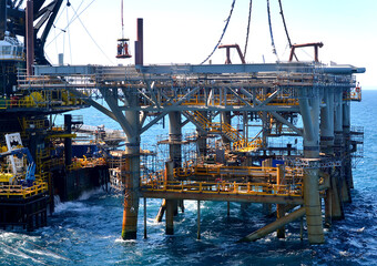 workers are transported to the topside section of an offshore platform lowered onto the jacket...