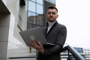 portrait of a young businessman with a laptop outside the office